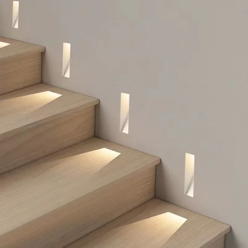Smalle ingebouwde wandlampen langs een houten trap, die elke trede met warm licht beschijnen 6