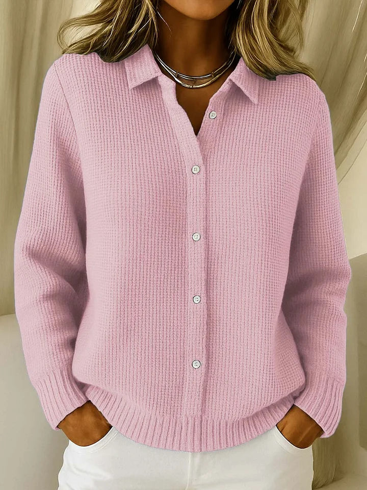 Dezelfde gebreide trui met knoopjes en kraag in roze, gedragen door een model met een zilverkleurige ketting. 2