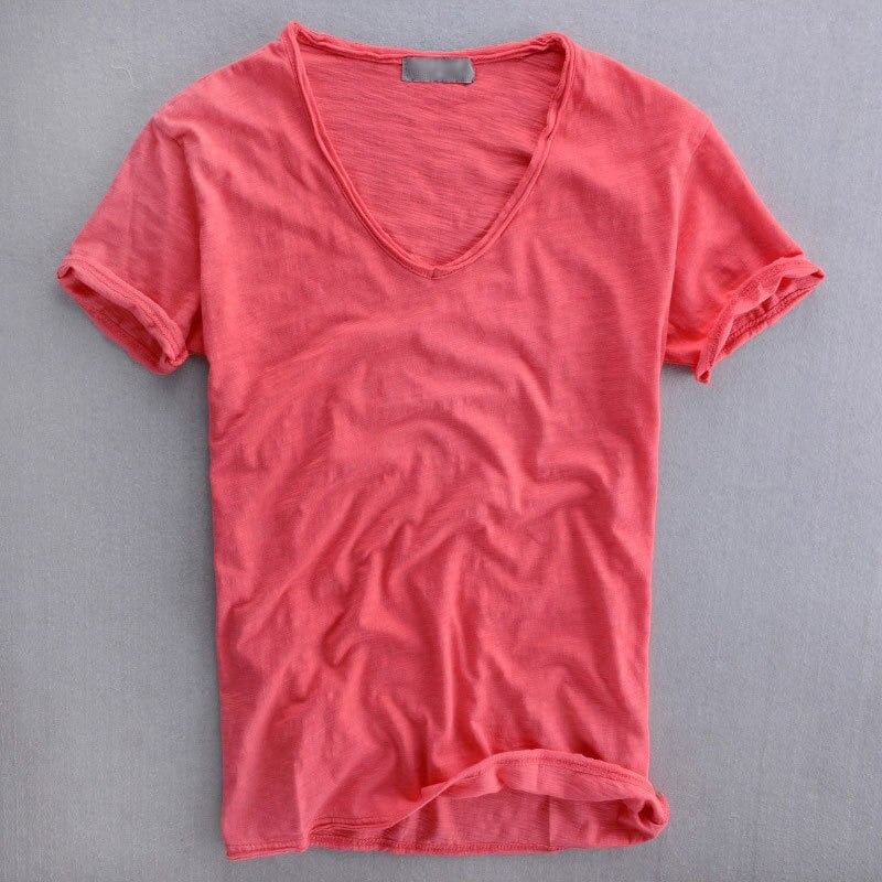 Koraalrood T-shirt met diepe V-hals en opgerolde mouwen, plat gefotografeerd op een grijze ondergrond, met zichtbare getextureerde garenstructuur. 3