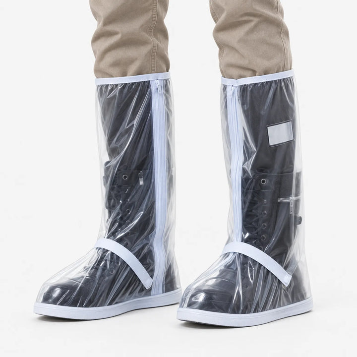 Doorzichtige regenoverschoenen met witte rits en bandjes, over zwarte veterlaarzen gedragen, gezien van voren tegen een witte achtergrond. 2