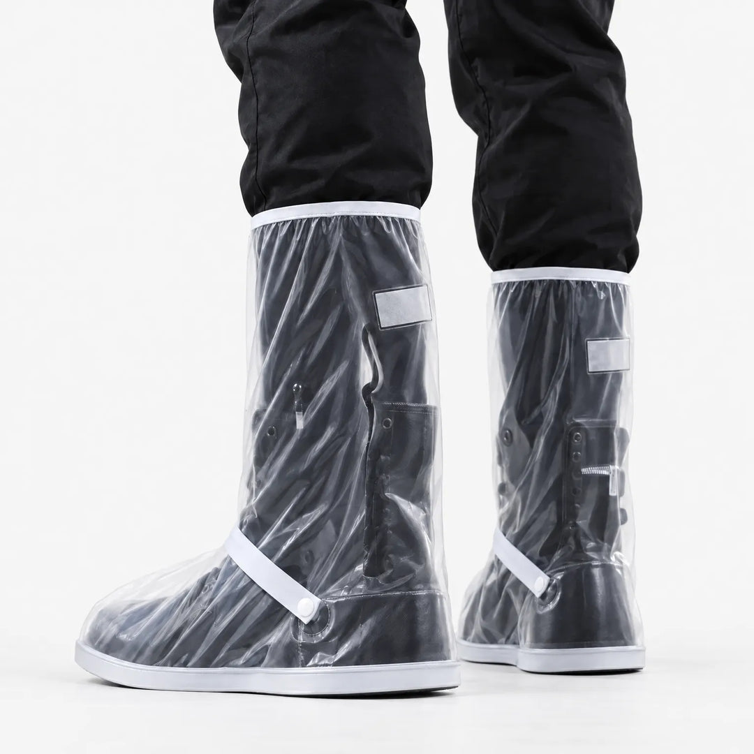 Achteraanzicht van doorzichtige regenoverschoenen met witte rand en bandje, gedragen over zwarte laarzen en onder een zwarte broek. 4