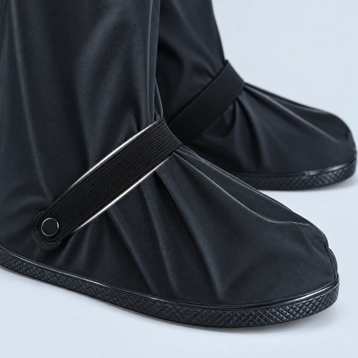 Close-up van de voorkant van zwarte regenoverschoenen met elastisch bandje, drukknoop en een zool met ruitvormig profiel. 6