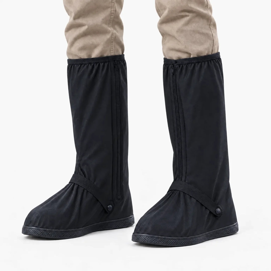 Zwarte regenoverschoenen met rits aan de zijkant en bandje bij de voet, gedragen onder een beige broek, vooraanzicht op witte achtergrond. 7