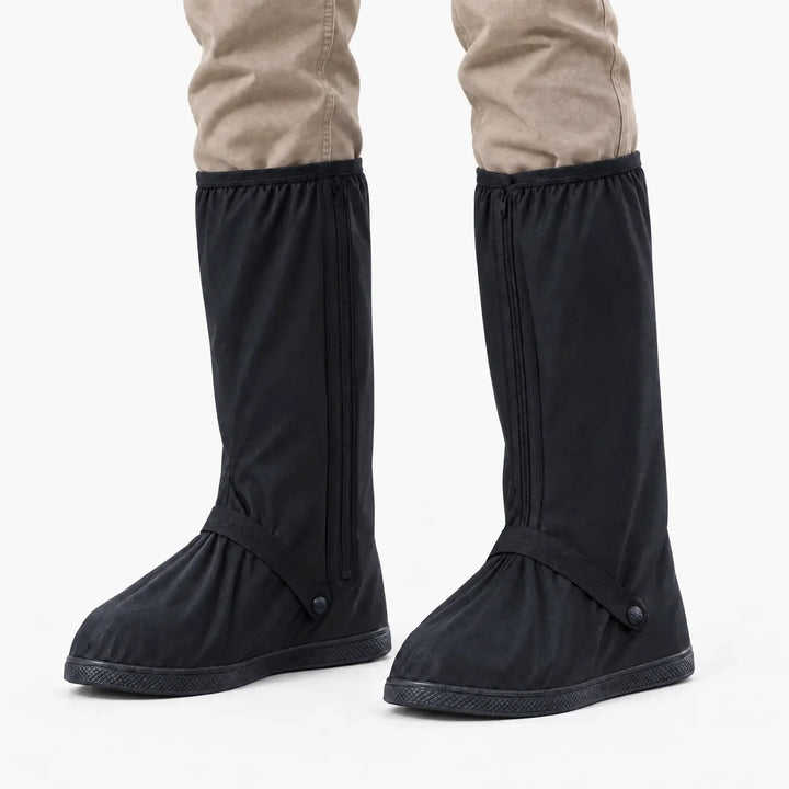 Zwarte regenoverschoenen met rits aan de zijkant en bandje bij de voet, gedragen onder een beige broek, vooraanzicht op witte achtergrond. 7