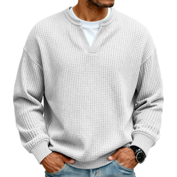 Dezelfde wafeltrui in lichtgrijs, gedragen door een model met wit shirt eronder en een spijkerbroek. 8