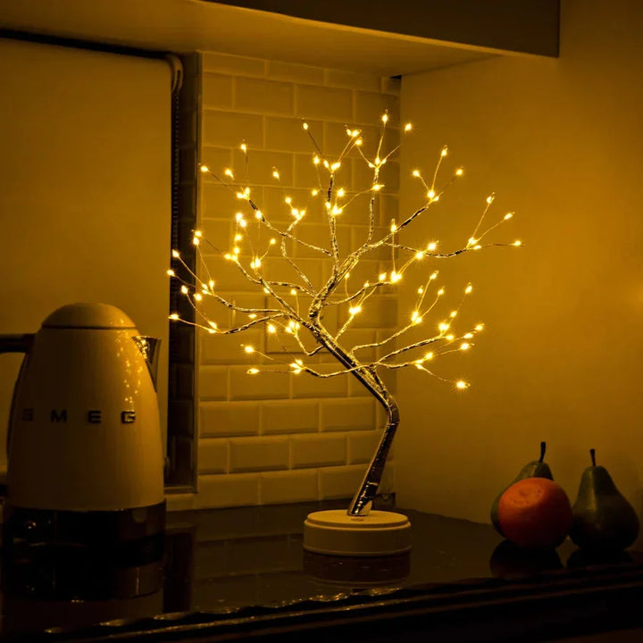 Verlichte boomlamp op een keukenblad naast een waterkoker en drie stuks fruit 5