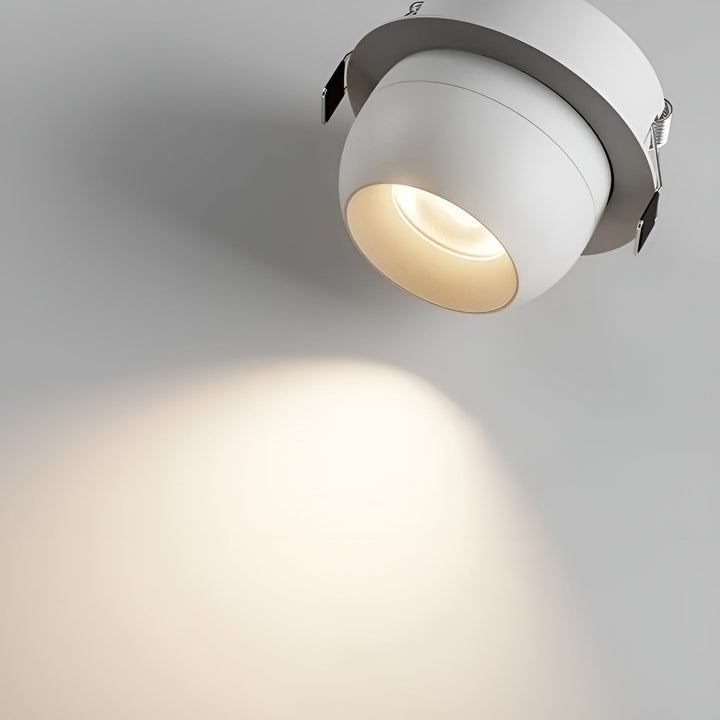 Close-up van een witte inbouwspot met veerklemmen aan de rand, die een warme lichtkegel werpt 4