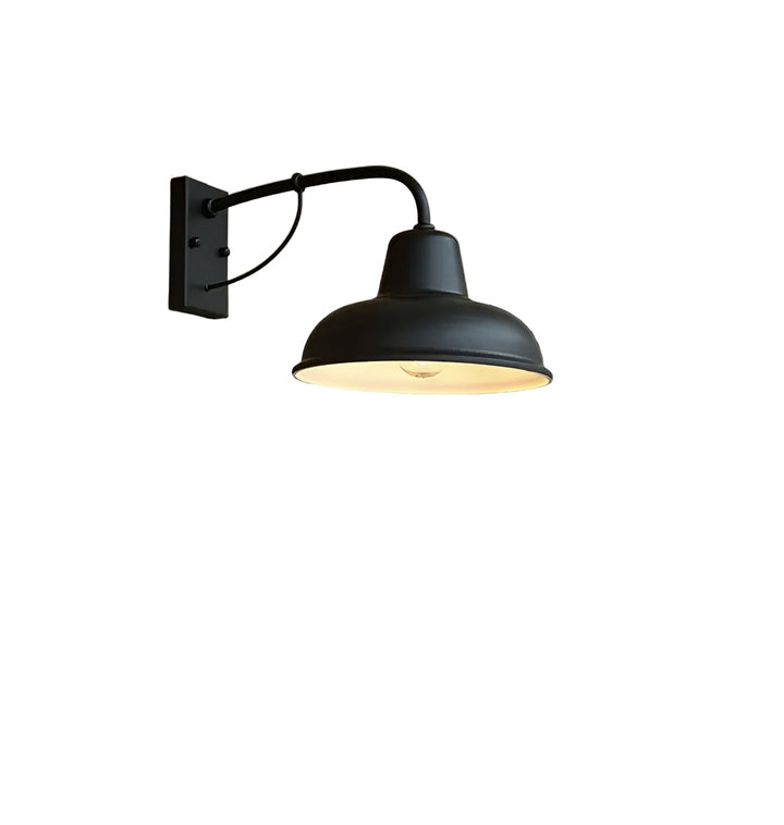 Zwarte wandlamp met gebogen arm, steunbeugel en koepelvormige kap, vrijstaand op een witte achtergrond met een zichtbare gloeilamp. 1