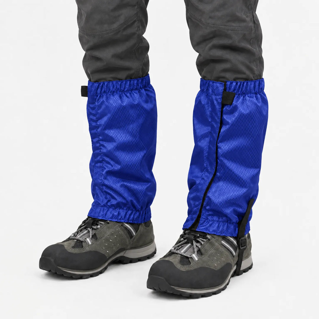 Blauwe gamaschen met ruitjesstructuur, gedragen over grijze wandelschoenen en donkere broek op een witte achtergrond. 8