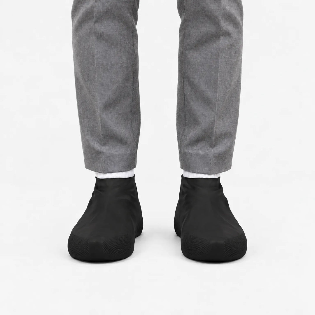 Voorkant van zwarte overschoenen gedragen met een grijze pantalon en witte sokken, met geribbeld profiel op de neus. 9