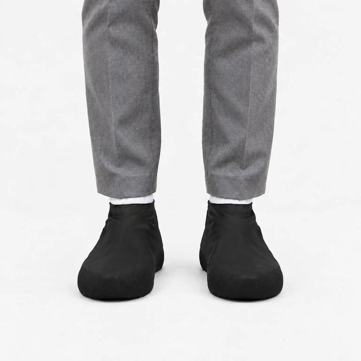 Voorkant van zwarte overschoenen gedragen met een grijze pantalon en witte sokken, met geribbeld profiel op de neus. 9