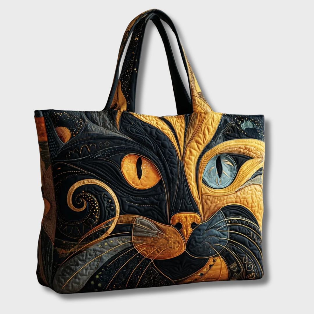 Schuine zijaanzicht van de gewatteerde tas met kattenkopmotief en twee zwarte hengsels tegen een lichte achtergrond 2