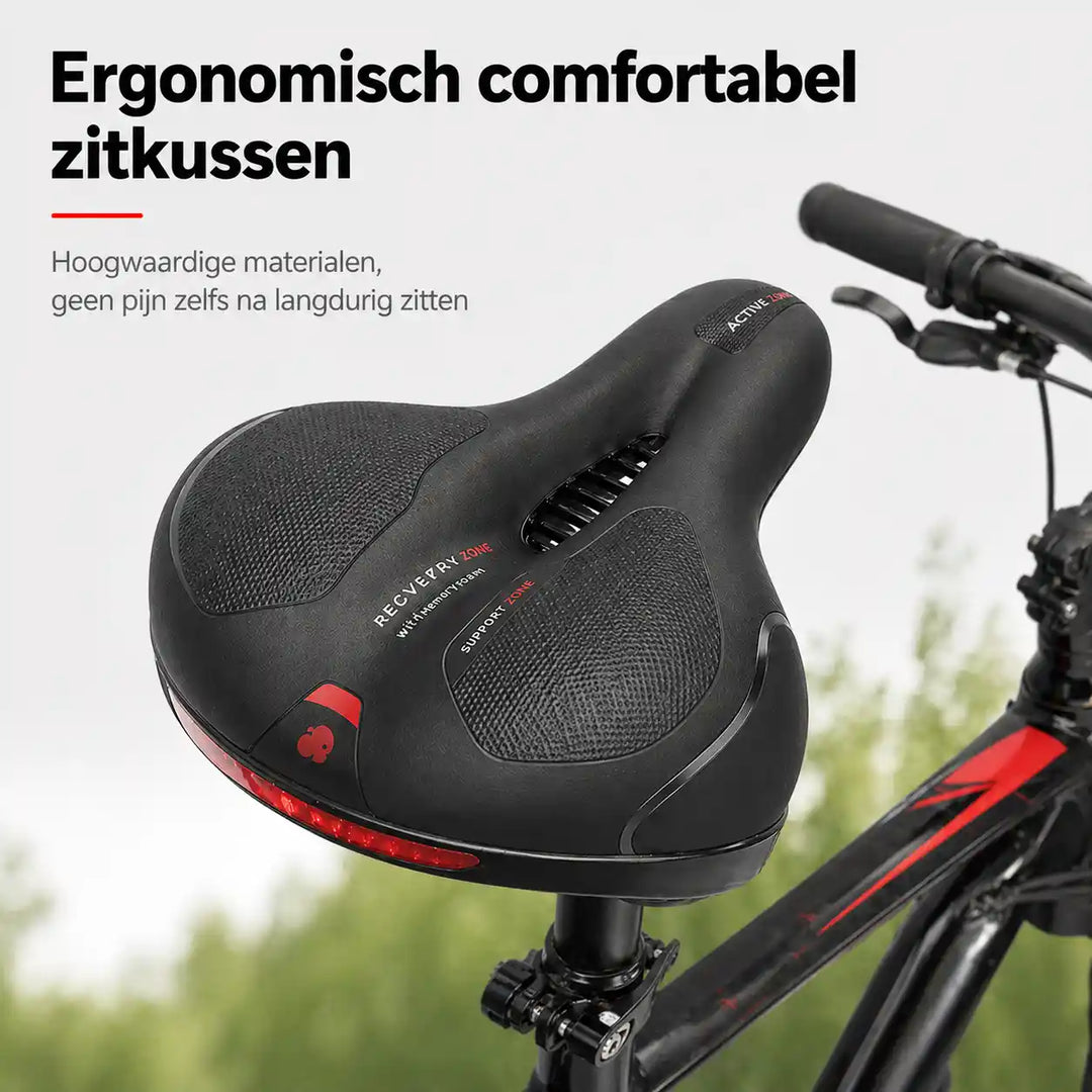 Zwart fietszadel met uitsparing en rode reflectiestrip, schuin van boven gezien op een fiets met groene natuur op de achtergrond. 1