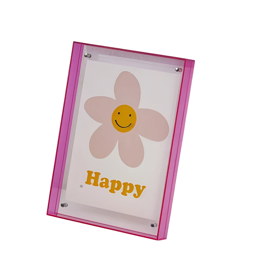 Doorzichtige acrylfotolijst met neonroze zijkanten, schuin weergegeven, met een print van een lachende roze bloem met gele smiley erin. 1