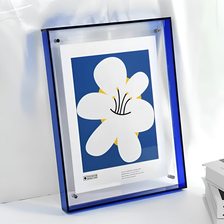 Blauwe acryllijst met doorzichtige voorkant en bevestigingsschroefjes, schuin tegen een lichte muur, met een poster van een grote witte bloem op blauwe achtergr 14