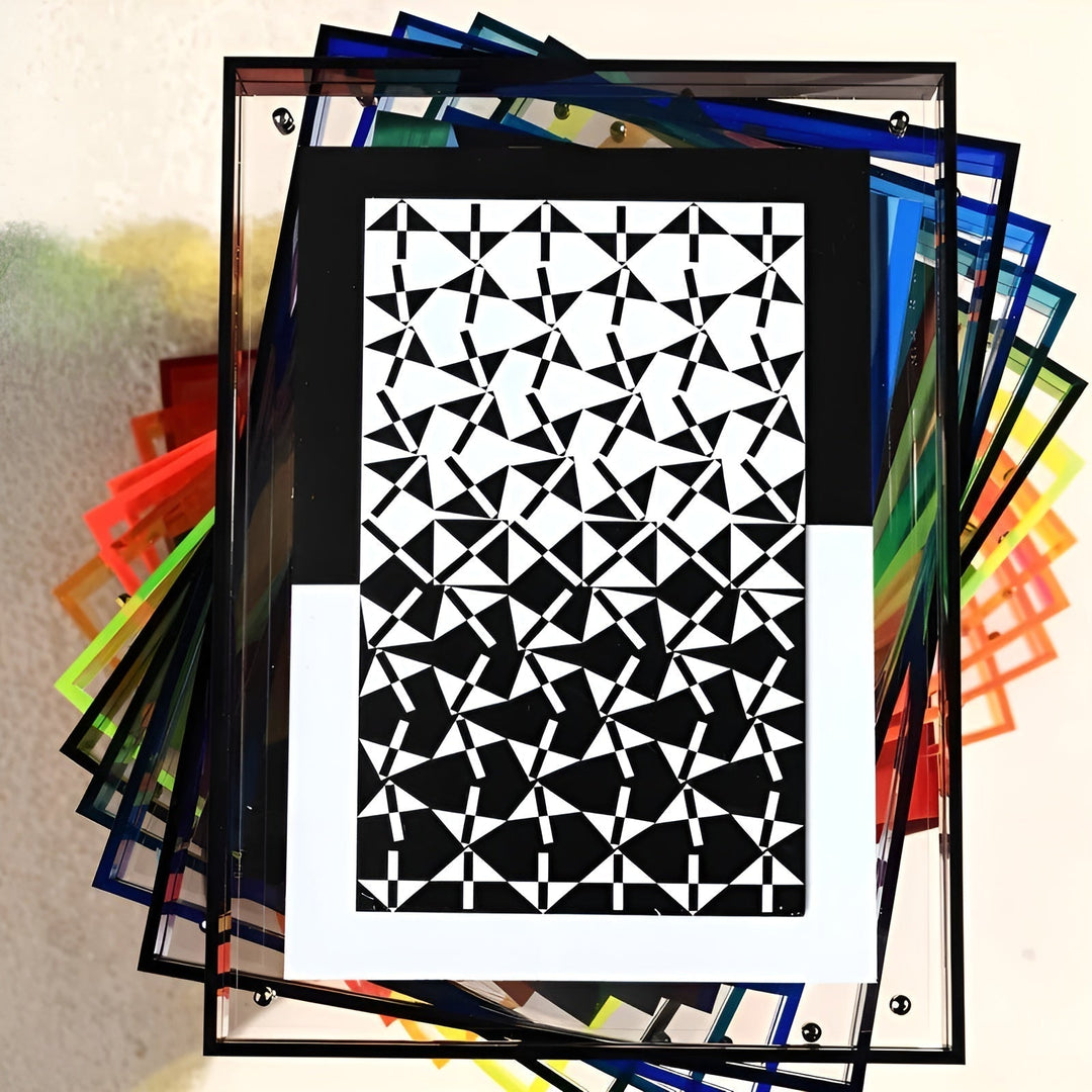 Bovenaanzicht van een waaier van gestapelde acrylframes in felle kleuren, met voorop een zwart-wit grafisch patroon achter helder acryl. 8