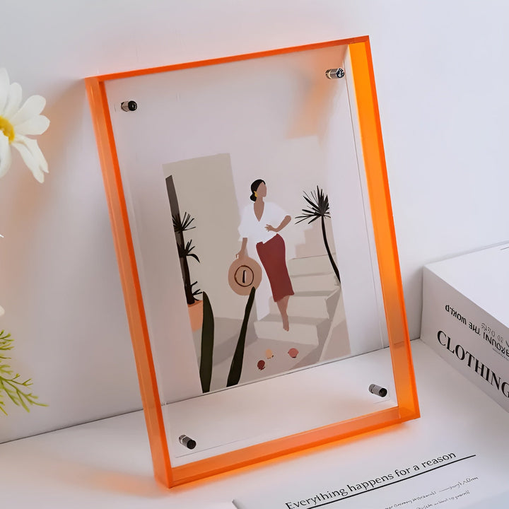 Fotolijst van doorzichtig acryl met oranje neonrand, schuin tegen een witte muur, met een illustratie van een vrouw met strohoed en bloemen ernaast. 10