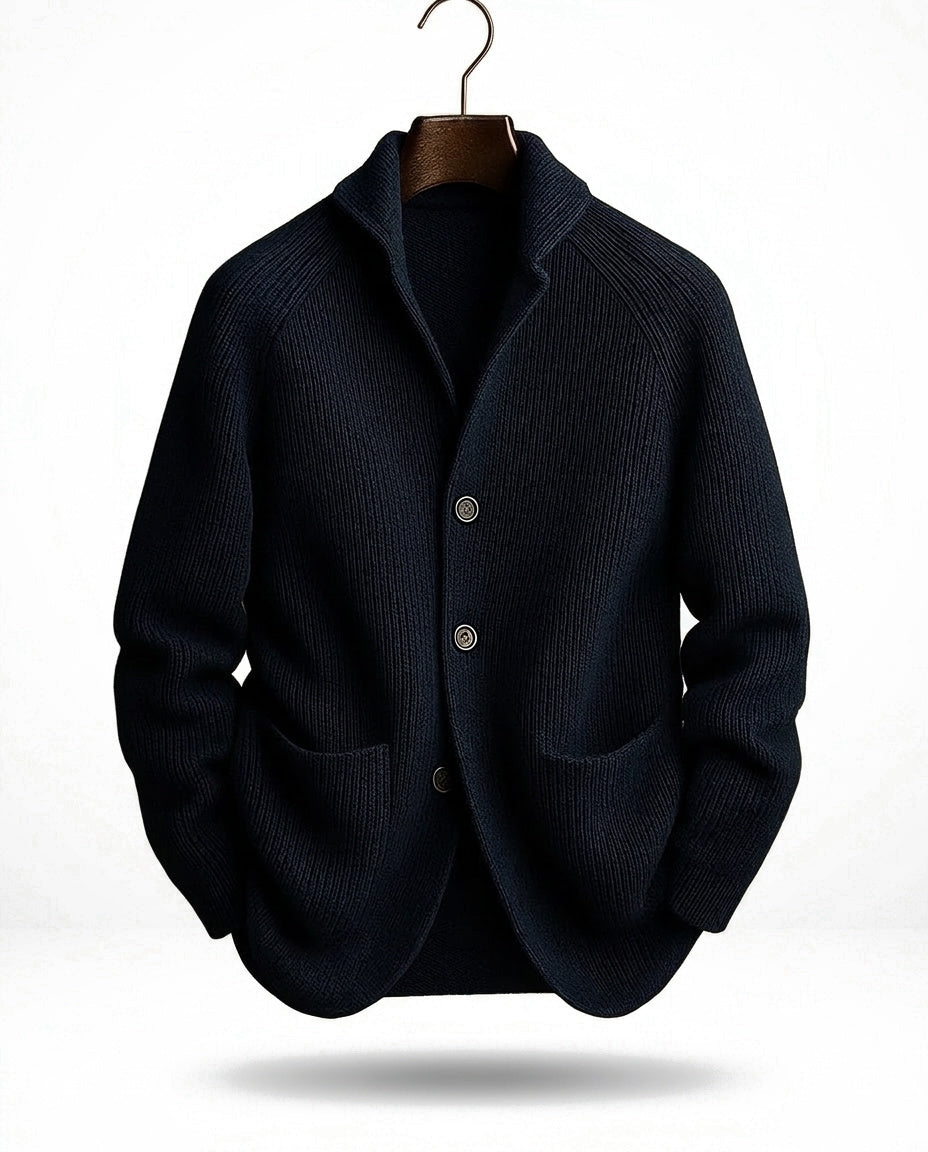 Donkerblauw geribd vest hangend aan een kleerhanger, met sjaalkraag, knoopsluiting en twee grote opgezette zakken. 3