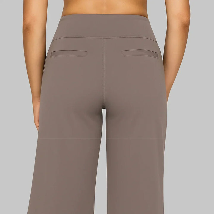 Achterkant van de taupe broek met brede tailleband, twee paspelzakken en een middennaad. 4