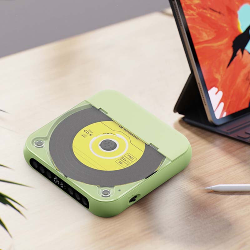 Groene cd-speler met gesloten doorzichtige klep op een houten bureau naast een tablet en een stylus. 12