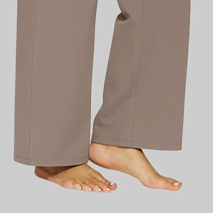 Detail van de pijpuiteinden van de taupe broek met zichtbare zoomnaad en blote voeten van de draagster. 5