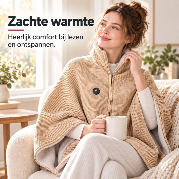 Vrouw in beige deken met rits zit met een mok op een crèmekleurige fauteuil bij het raam 6