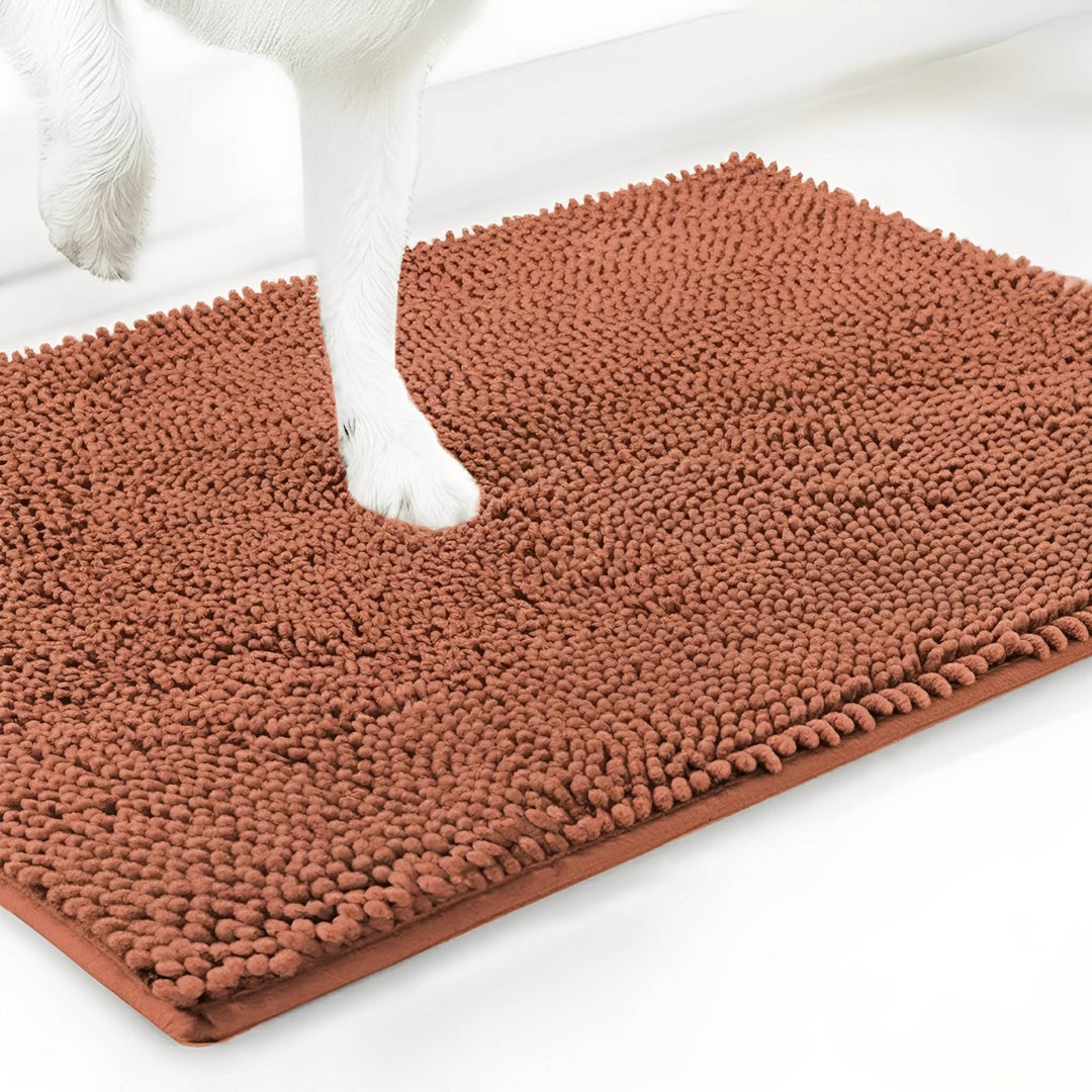 Terracotta-oranje chenille mat van dichtbij, met een witte hondenpoot die in de zachte vezels zakt. 16