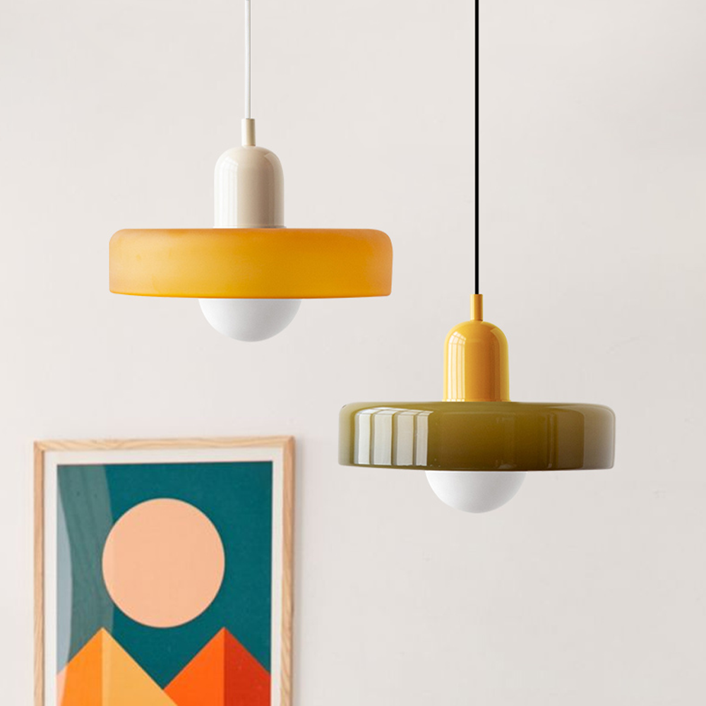 Twee hanglampen naast elkaar: een oranjegele kap met crèmekleurige fitting en een olijfgroene kap met gele fitting 27
