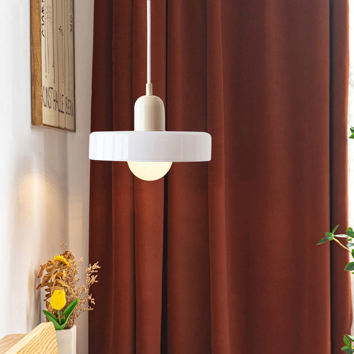Witte hanglamp met crèmekleurige fitting hangt voor een roestbruin gordijn naast gedroogde bloemen 46
