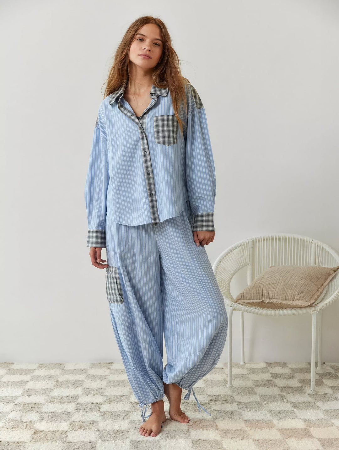 Volledig model in de blauw gestreepte set met grijs geruite details en een wijde broek met opgetrokken, vastgestrikte pijpen, op blote voeten. 7