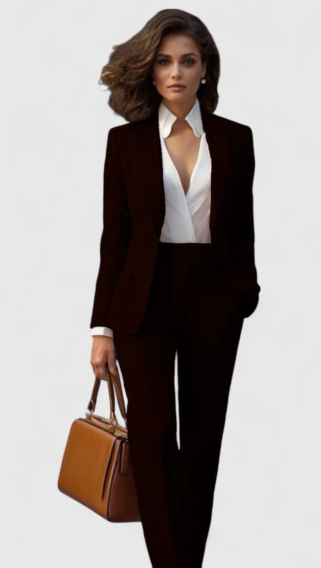 Model in zwart kostuum met witte blouse met diepe halslijn en een bruine leren handtas. 7