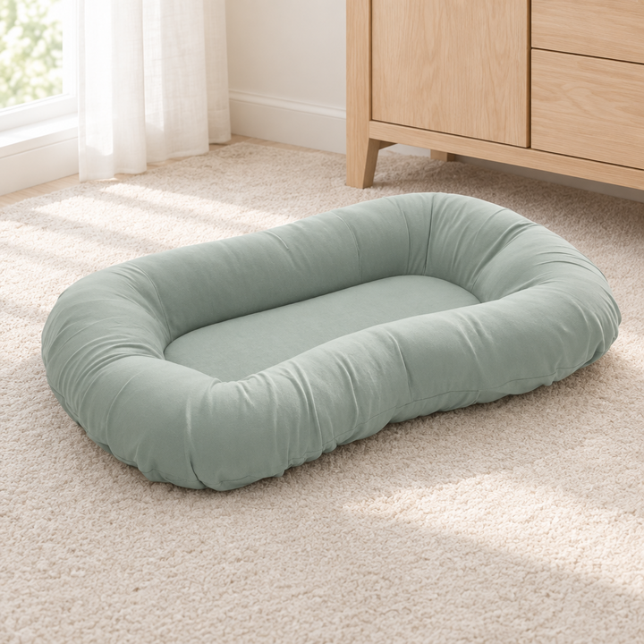 Leeg grijsgroen kussen op een crèmekleurig vloerkleed naast een houten commode 8