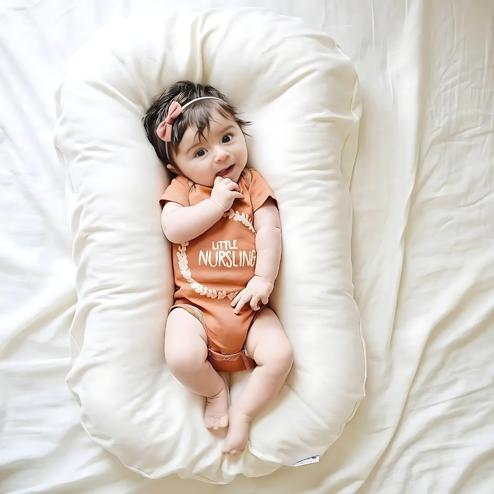 Baby met roze haarstrikje en oranje romper ligt op een wit kussen op een laken 5