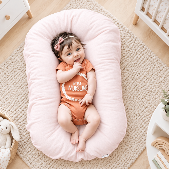 Lachende baby in oranje romper ligt op roze kussen in een gezellige babykamer 1
