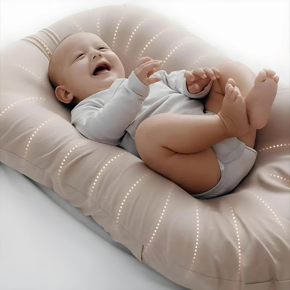 Close-up van een lachende baby met opgetrokken beentjes op een beige kussen met stippellijnen 2