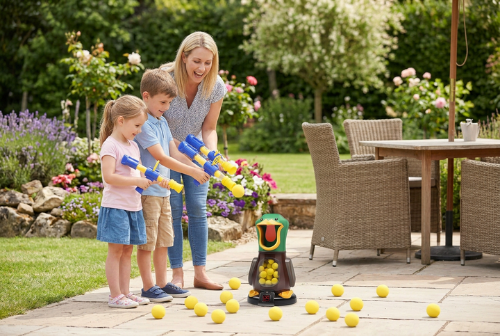 Moeder en twee kinderen richten blauw-gele schuimballenpistolen op de eendenmachine op een zonnig terras 1