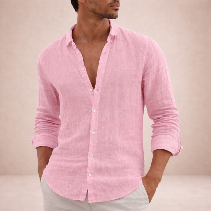 Model draagt roze linnen overhemd met opgerolde mouwen en beide handen in de zakken van een lichte broek. 4