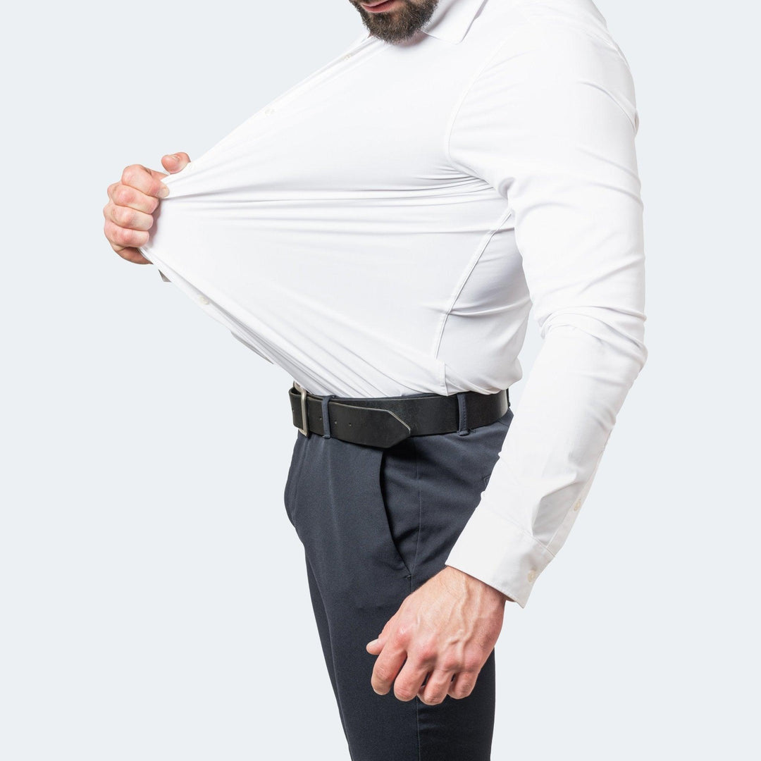 Wit overhemd gedragen met riem en donkere pantalon, de stof wordt bij de borst uitgerekt om de elasticiteit te tonen. 3