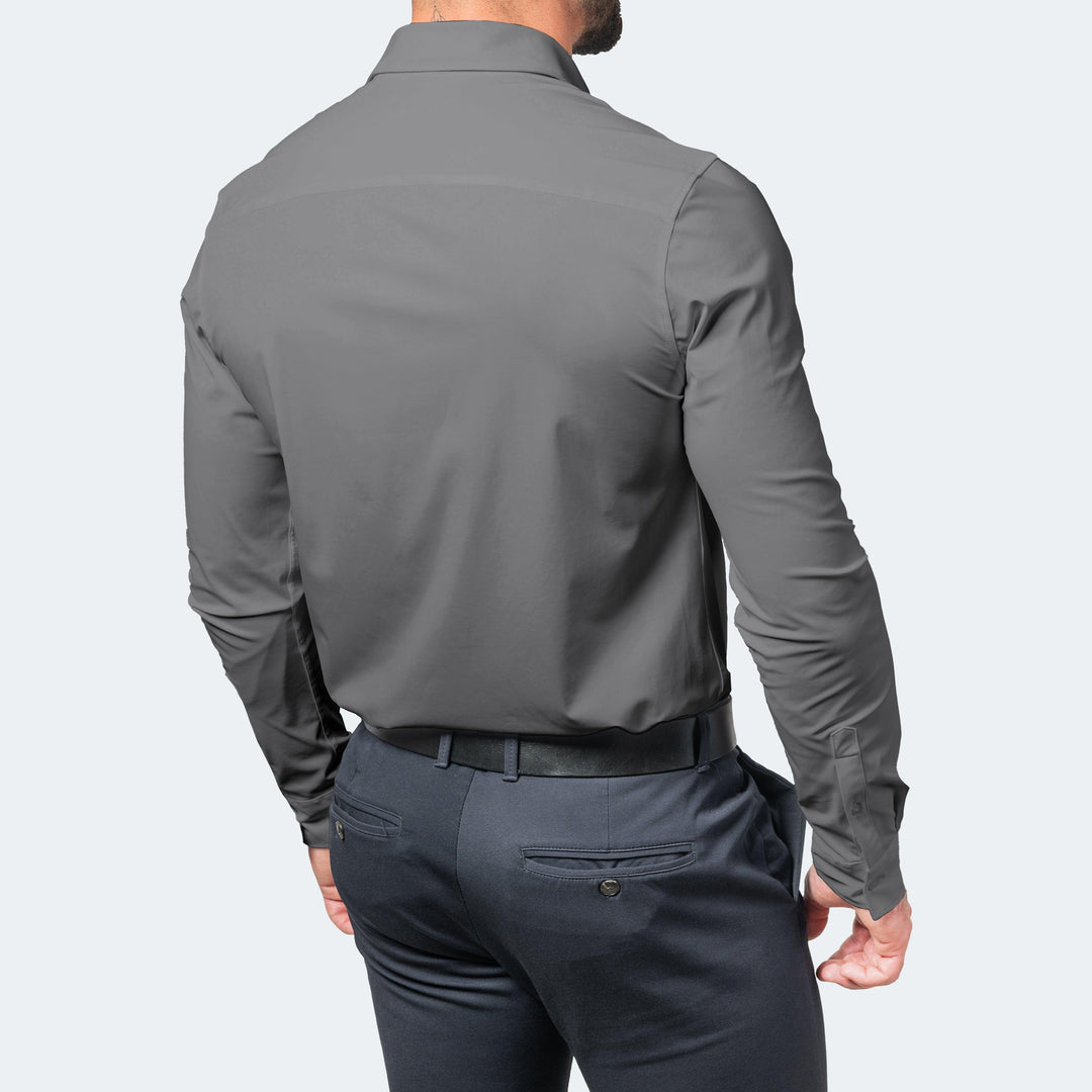 Grijs overhemd van achteren gedragen met riem en donkere pantalon, met een glad rugpand zonder plooien. 6