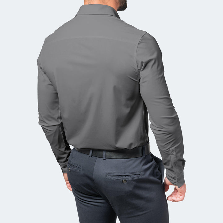 Grijs overhemd van achteren gedragen met riem en donkere pantalon, met een glad rugpand zonder plooien. 6