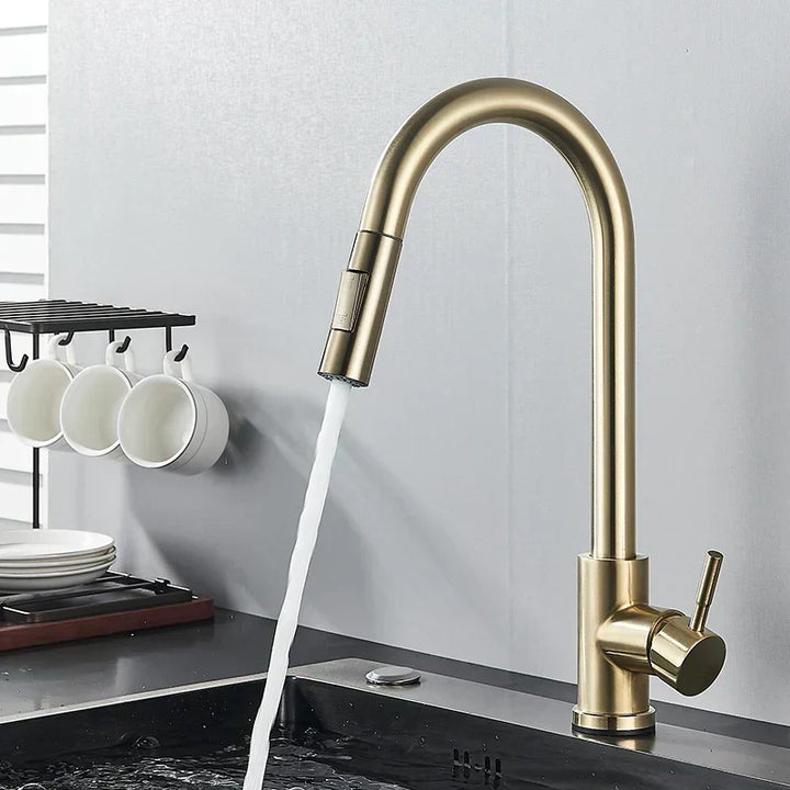 Geborsteld gouden keukenkraan met lopend water boven een zwarte spoelbak, naast een rekje met witte kopjes en borden. 6