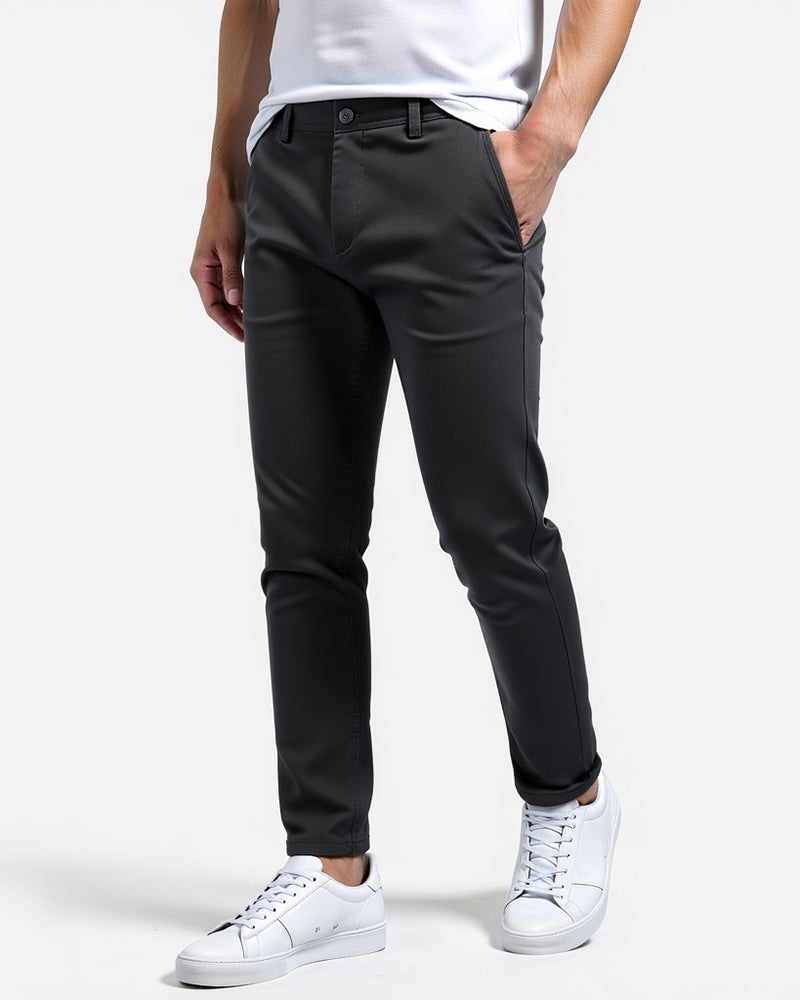 Donkergrijze chino schuin van voren, gedragen met wit shirt en witte sneakers, een hand in de zak. 12