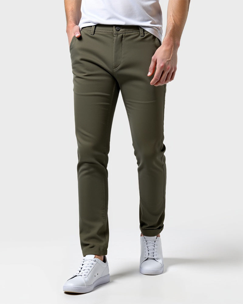 Olijfgroene chino van voren gedragen met wit shirt en witte sneakers, één hand in de zak. 13