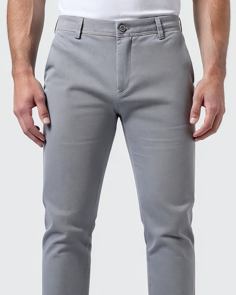 Close-up van de voorkant van de lichtgrijze chino met knoopsluiting, riemlussen en ritssluiting in de tailleband. 5