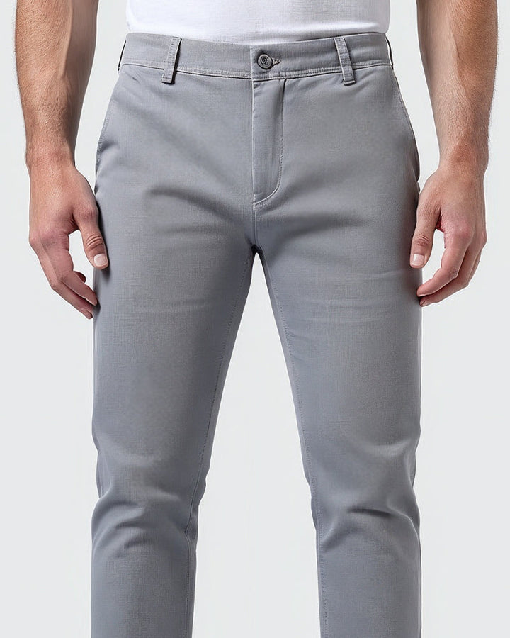 Close-up van de voorkant van de lichtgrijze chino met knoopsluiting, riemlussen en ritssluiting in de tailleband. 5