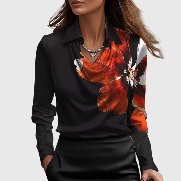 Model draagt de zwarte blouse met grote oranjerode bloemprint op de rechterkant, gedrapeerde hals en een zwarte rok. 6