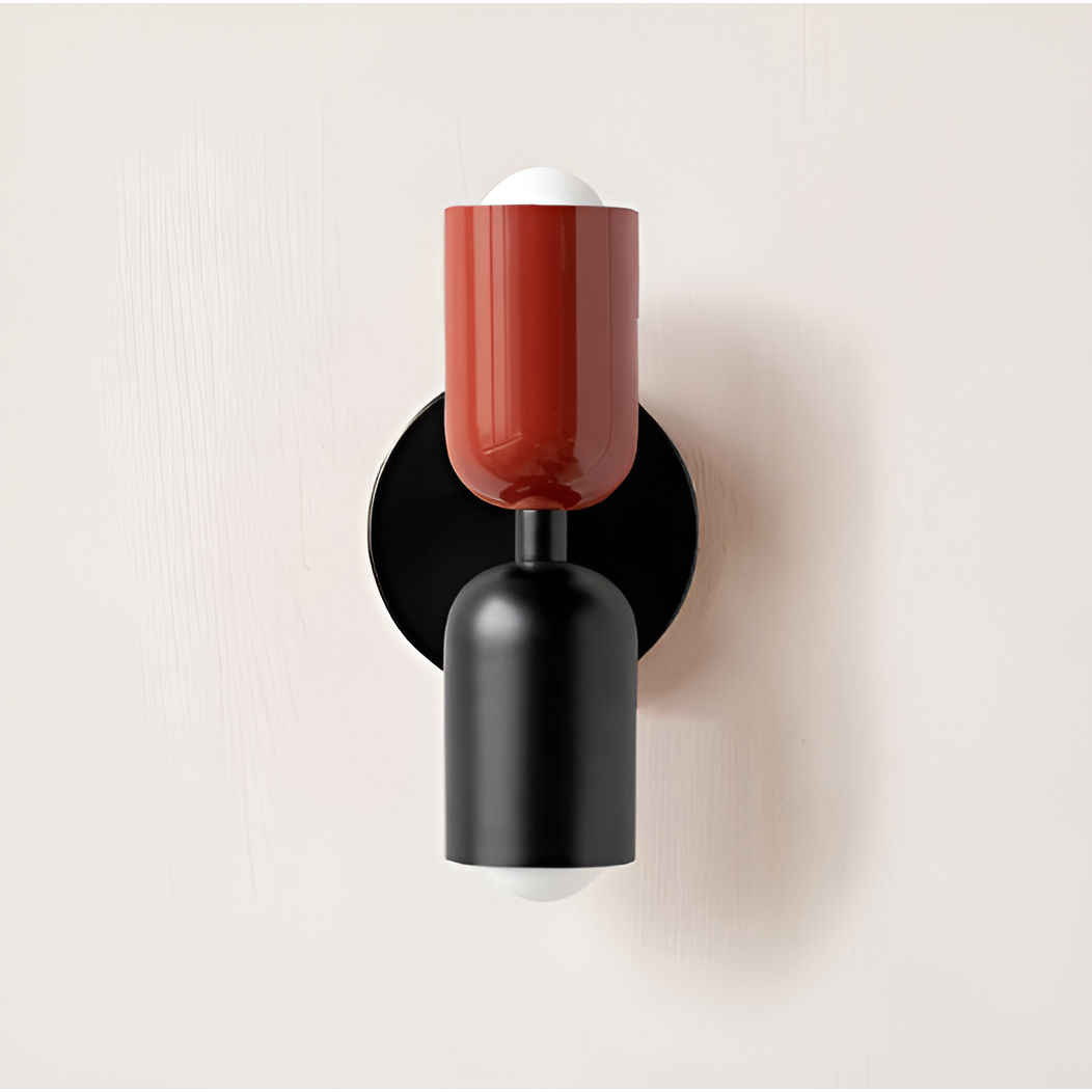 Wandlamp met rode bovenkap en zwarte onderkap op een zwarte ronde plaat, tegen een lichte muur. 22