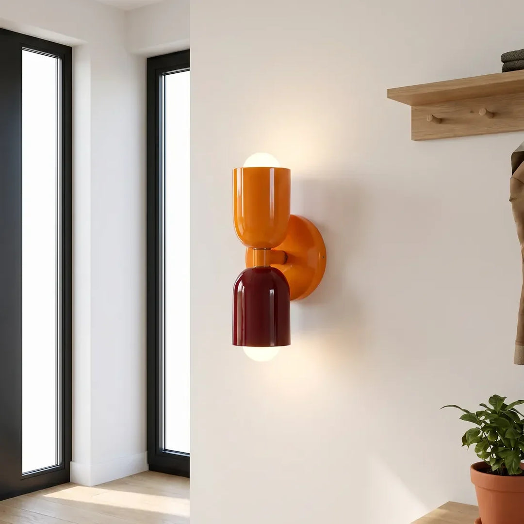 Wandlamp in oranje en bordeauxrood in een hal, met hoge ramen, een houten kapstokplank en een plant in terracotta pot. 11