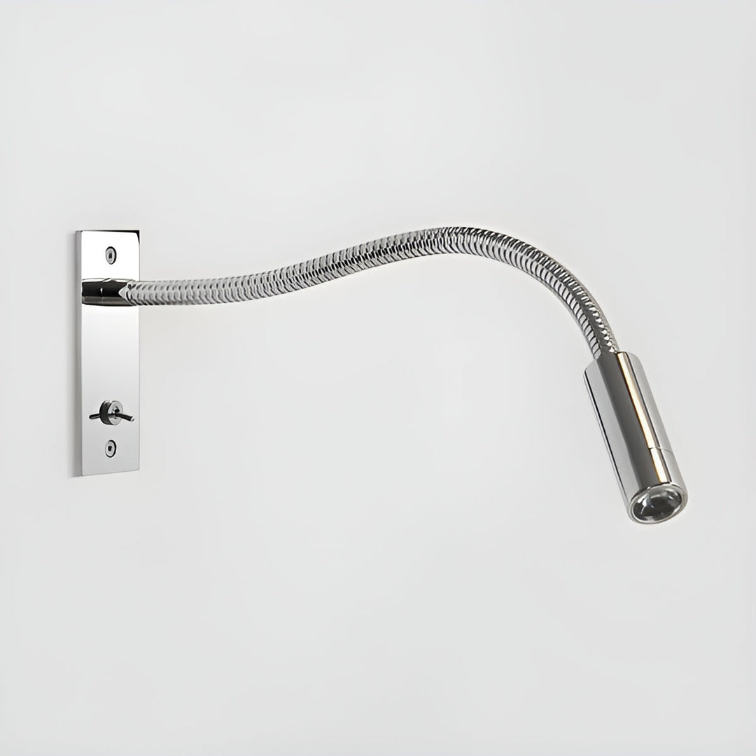 Wandlamp in glanzend gepolijst chroom met gegolfde flexibele arm, tuimelschakelaar en cilindrische lampkop tegen een lichte muur. 12