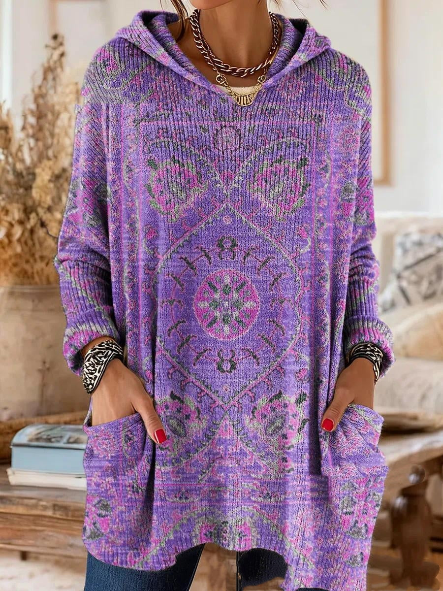 Dezelfde tuniek in paars met roze en groen medaillonmotief, gedragen door een model met de handen in de zakken. 2